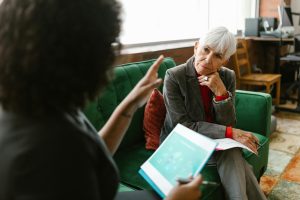 pexels photo 8124378 8124378 Elderly woman in corporate attire attentively listens during an indoor meeting.